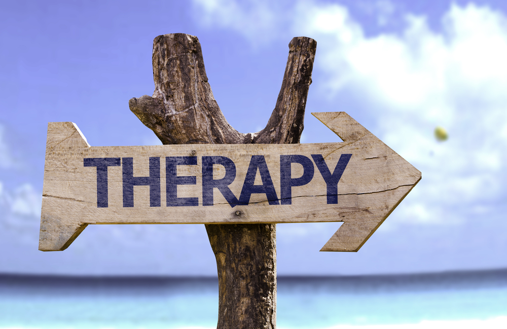 Therapy wooden sign with a beach on background